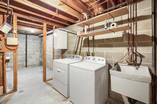 Offering exceptional functionality and abundant storage, the lower-level utility and laundry area provides the practical space every homeowner needs. The spacious laundry zone features a full-size washer and dryer, utility sink, & convenient shelving