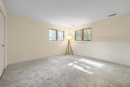 Both lower level bedrooms feature brand-new plush carpeting, fresh neutral finishes, and large windows that bring in natural light while showcasing peaceful views of the mature backyard.
