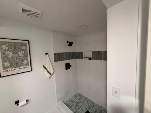 The standout feature is the stunning custom-tiled walk-in shower, showcasing crisp white tile, an elegant accent band, built-in shower niche, and sleek matte black fixtures that create a sophisticated spa-like feel.