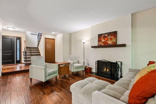 18x12 Main Floor Living room with Hardwood floors, Fireplace and north-facing windows opening up to the wooded back patio.