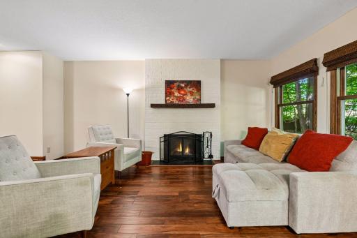 18x12 Main Floor Living room with Hardwood floors, Fireplace and north-facing windows opening up to the wooded back patio.