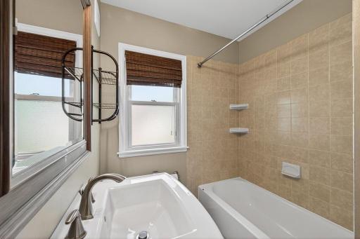 Main floor full bath with pedestal sink and tile surround.