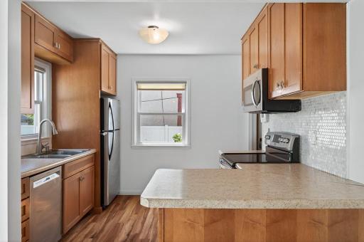Remodeled kitchen with stainless steel appliances, tile backsplash and new flooring.