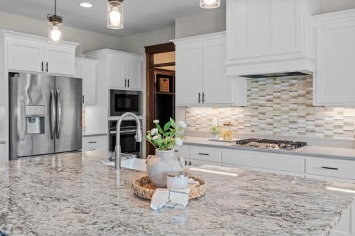 The gourmet kitchen has quartz counters and a oversized center island with a gorgeous granite counter and farm-style Kohler sink.