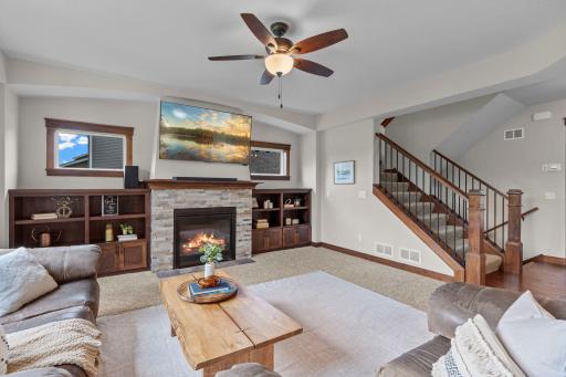 The living room is anchored by a gas fireplace with stone facade surrounded by custom, solid wood built-ins.
