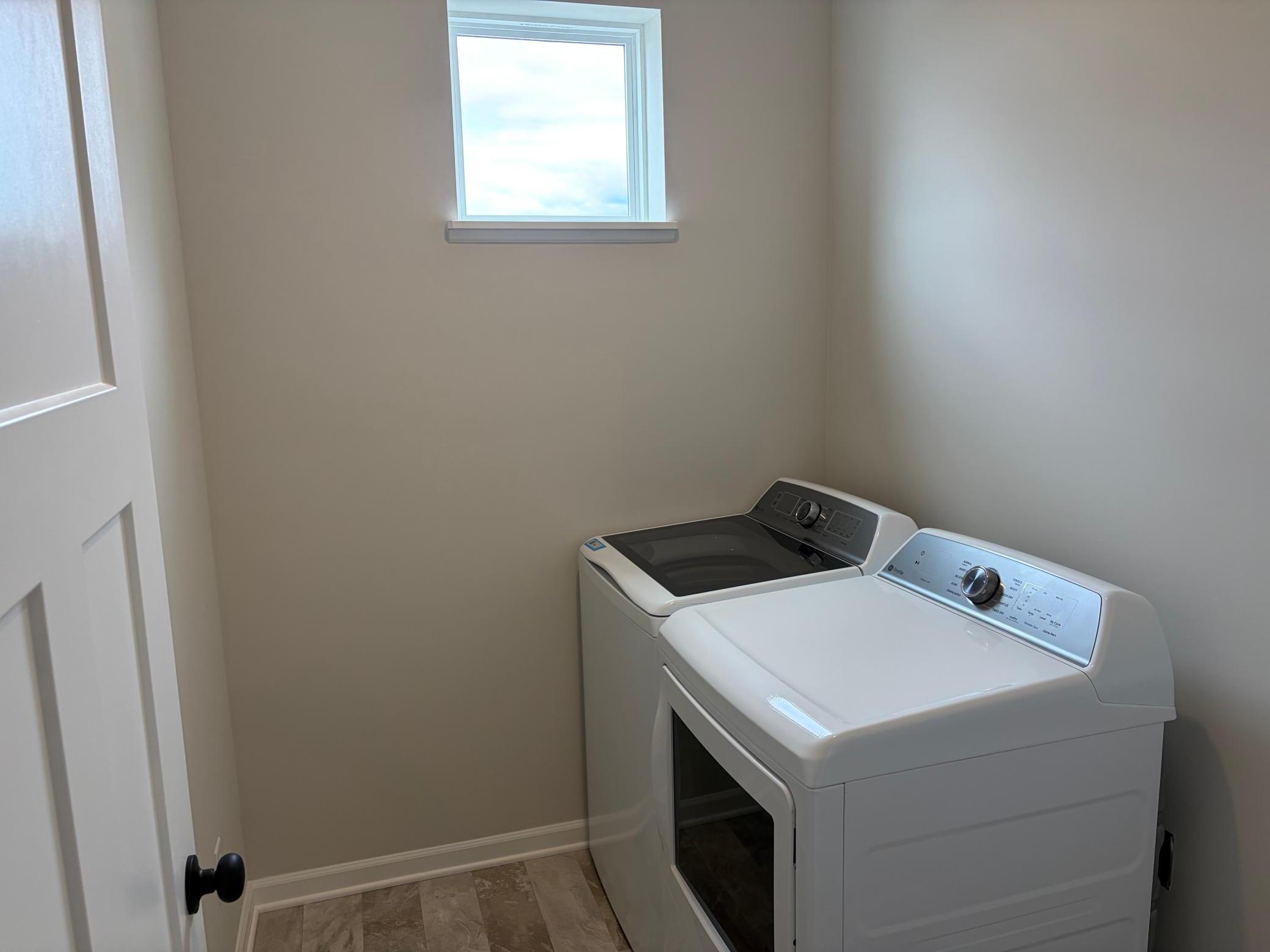 The laundry room features ample space with room above to add shelving.