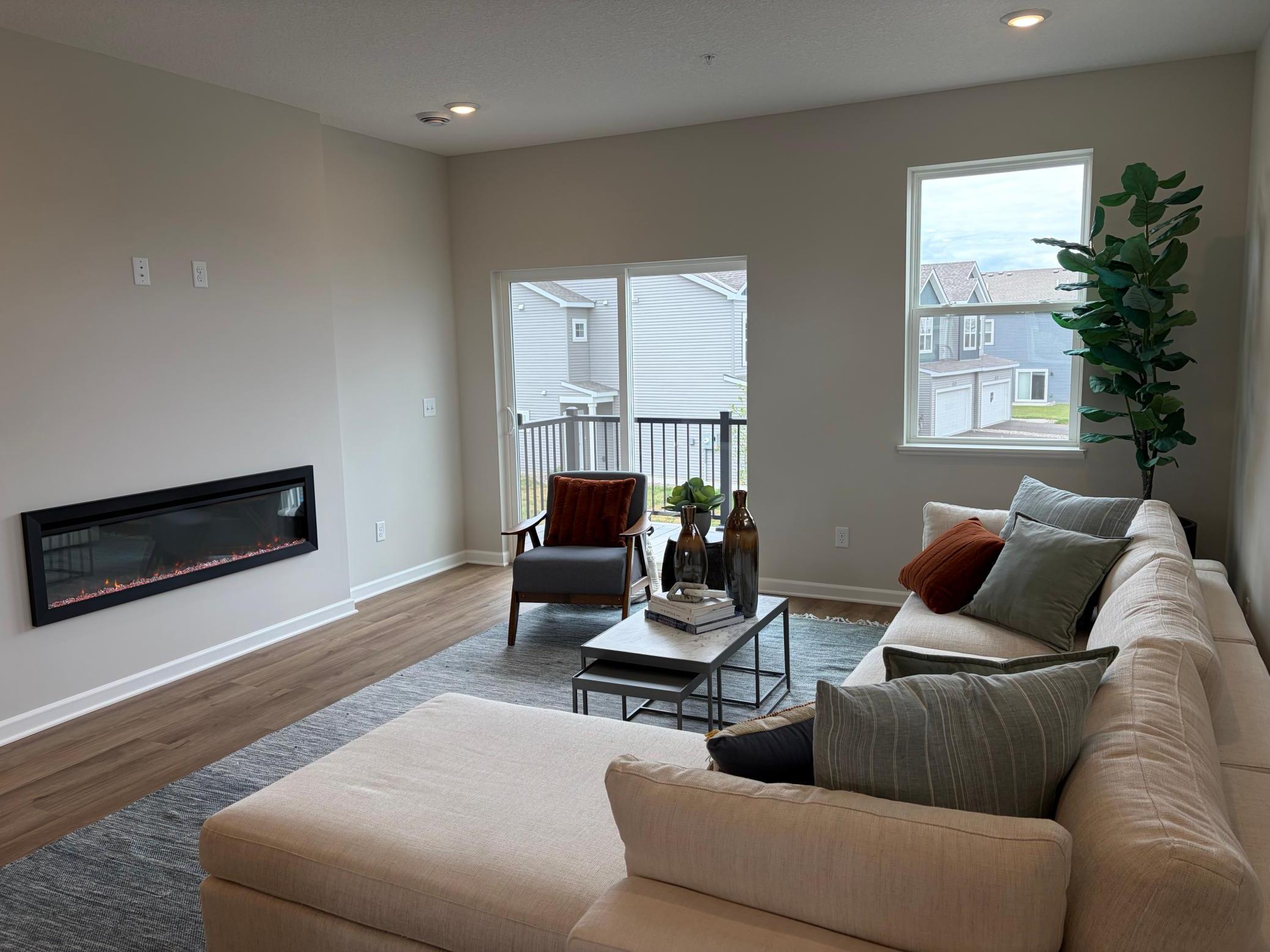 This spacious living room has excellent scenery featuring large windows, a fireplace, and enough space for even the biggest couches.
