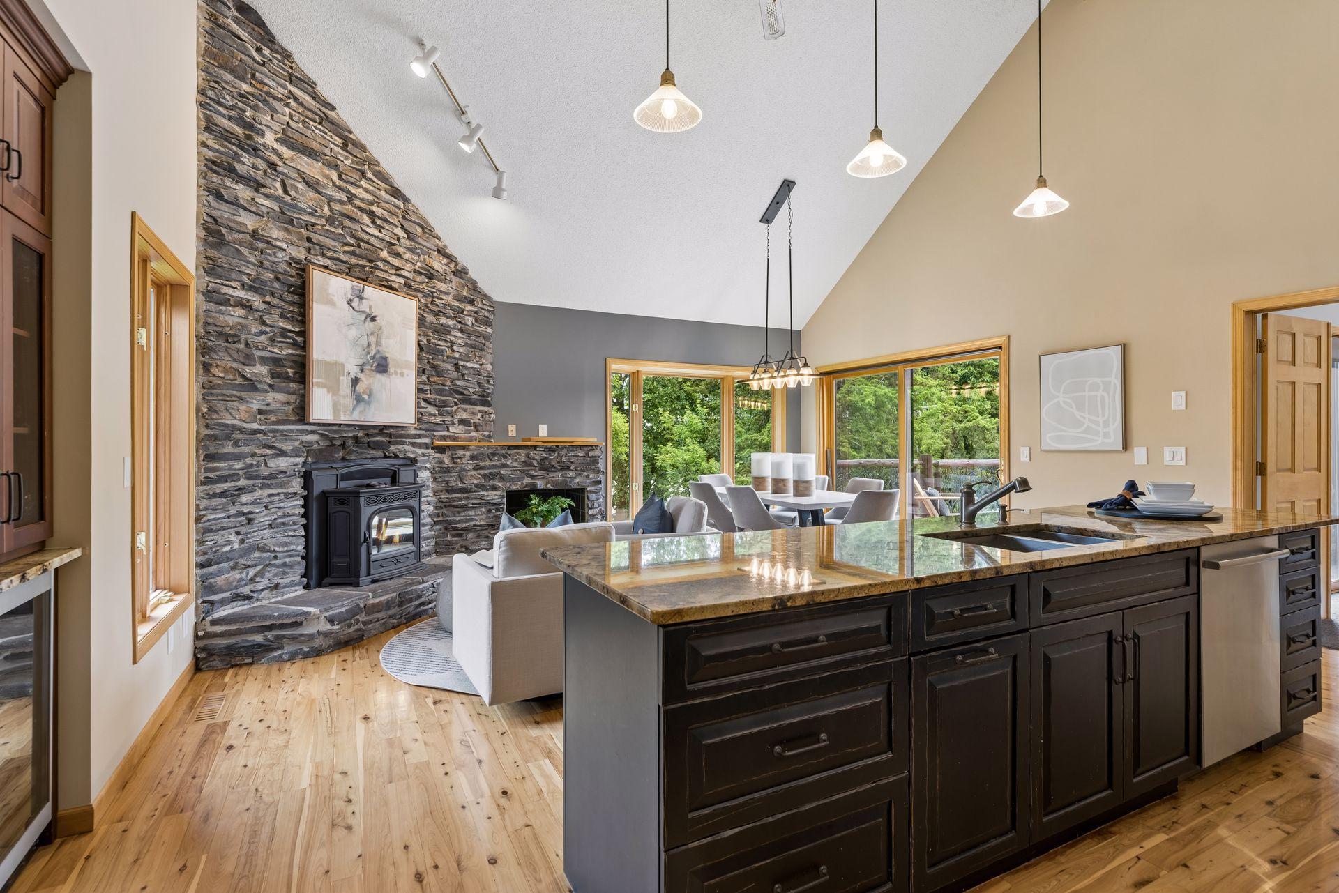 Stunning upper level great room with hardwood floors, floor-to-ceiling stone fireplace, newer pellet stove, two dining spaces, two sets of patio doors leading to deck overlooking the lake.
