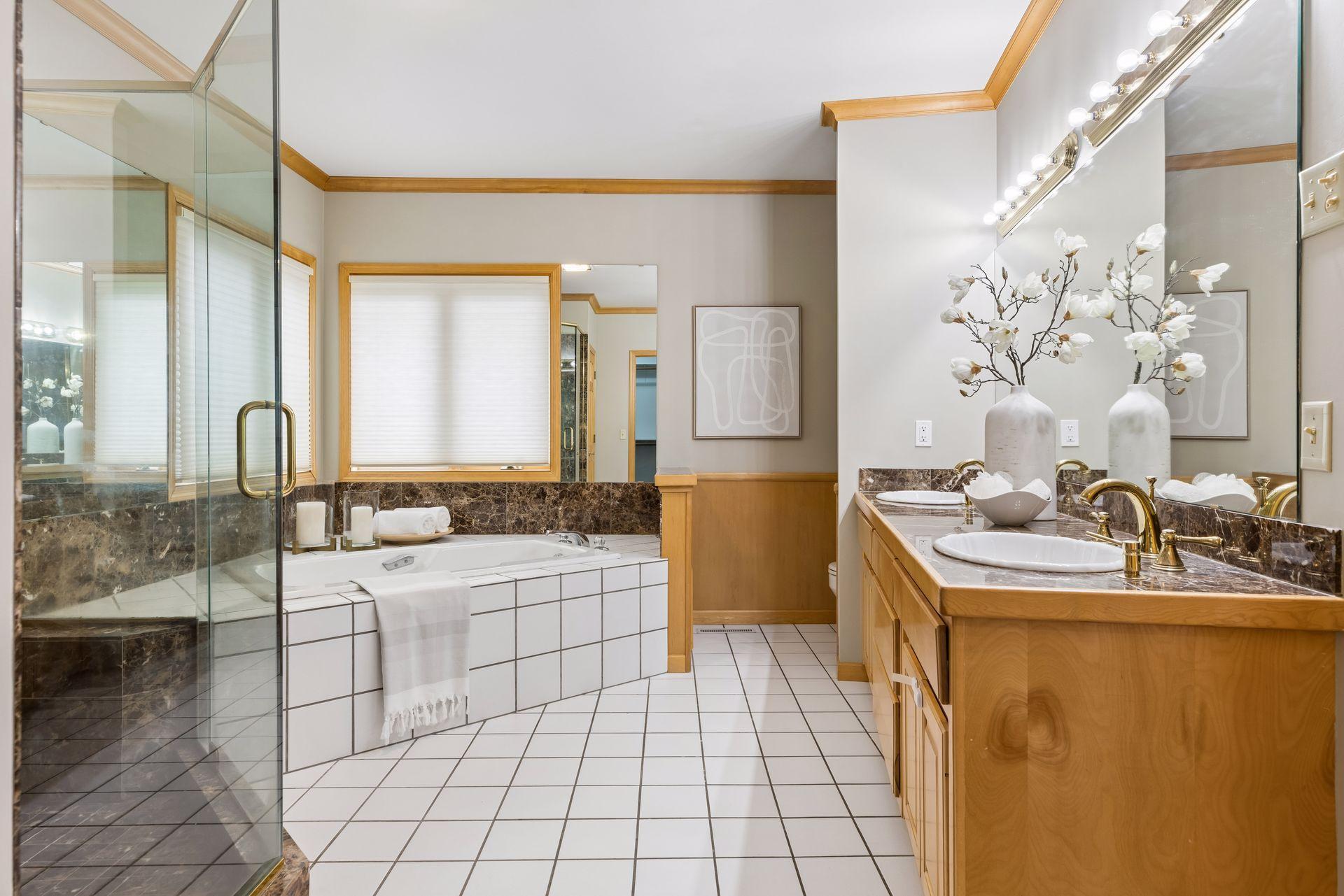 Private primary bathroom with corner jetted tub, separate tiled shower with glass door, dual sinks.