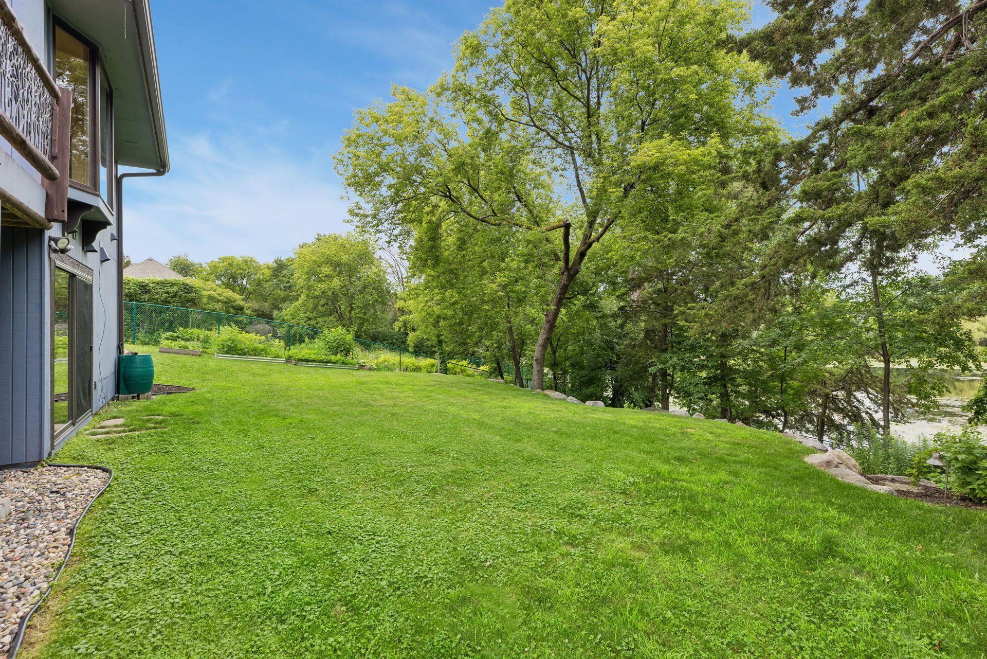Fenced, flat backyard leads to the landscaped firepit area near the water's edge.