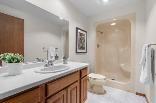 The lower level Â¾ bathroom includes a walk-in shower, single vanity, and tile flooring.