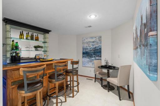 The custom bar area stands out with a sleek design, featuring a stylish bar with a light-up glass block backdrop, counter space, and built-in shelvingâperfect for hosting and entertaining guests.