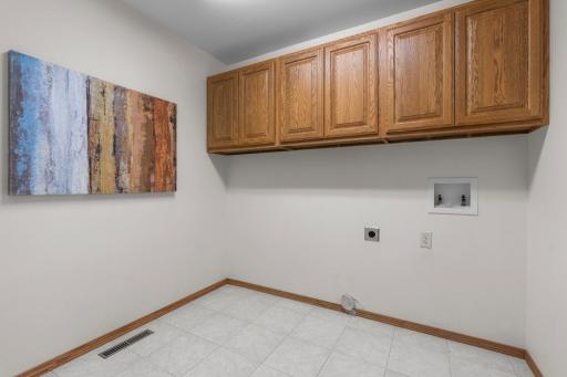 Convenient main-level laundry room with washer and dryer hookups, plus overhead cabinetry for added storage and organization.