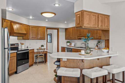 This kitchen is a chefâs dream, featuring an abundance of custom cabinetry, expansive Corian countertops, and a peninsula with convenient breakfast bar seating.
