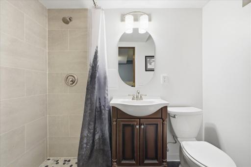 This new lower level private bathroom features a beautifully tiled walk-in shower, modern vanity, and contemporary fixtures. Clean lines and neutral finishes create a fresh, spa-inspired retreat.