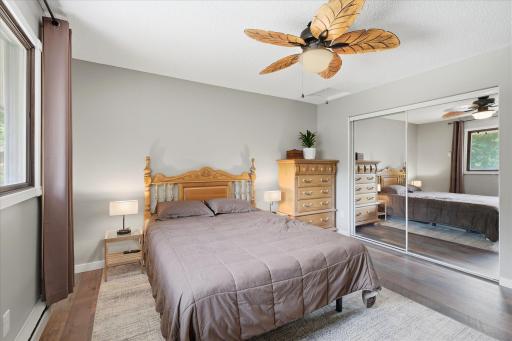 Mirrored closet on the far wall brings in additional light to this generous bedroom with fan.