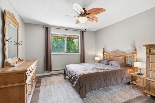 The spacious bedroom provides a peaceful retreat with large windows, neutral tones, and attractive flooring. Mature tree views create a relaxing and private atmosphere.