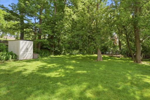 The expansive backyard and adjacent green space is surrounded by mature trees, offering privacy, shade, and plenty of space for recreation, gardening, or simply enjoying nature.