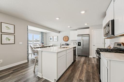 Thoughtfully designed kitchen with stainless appliance package including gas range, dishwasher and vented micro-hood. Photo of model home, color & options will vary.