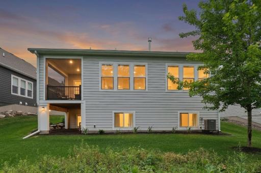At twilight, this elegant villa truly shines, with warm interior lighting glowing softly through expansive windows. The rear faÃ§ade opens to a peaceful outdoor setting, where the fading sky casts calming hues over the backyard and surrounding trees