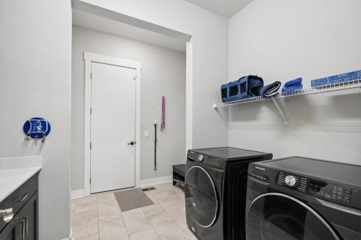 Conveniently located on the main level, this laundry room is designed with both efficiency and ease of use in mind. The space offers ample room for full-size washer and dryer units, along with additional counter space for folding, and organizing.