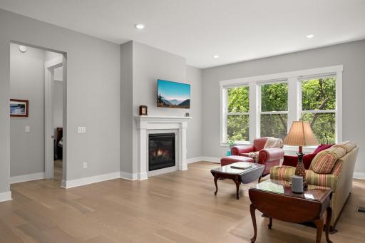 Spacious living room filled with natural light from large windows, featuring a cozy gas-burning fireplace that creates a warm and inviting atmosphere.