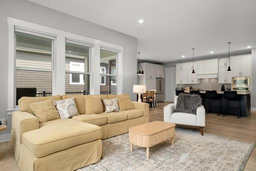Another view of the living room showcasing its bright, open layout. Large windows fill the space with natural light, while the comfortable seating area, and seamless flow into the adjoining spaces.