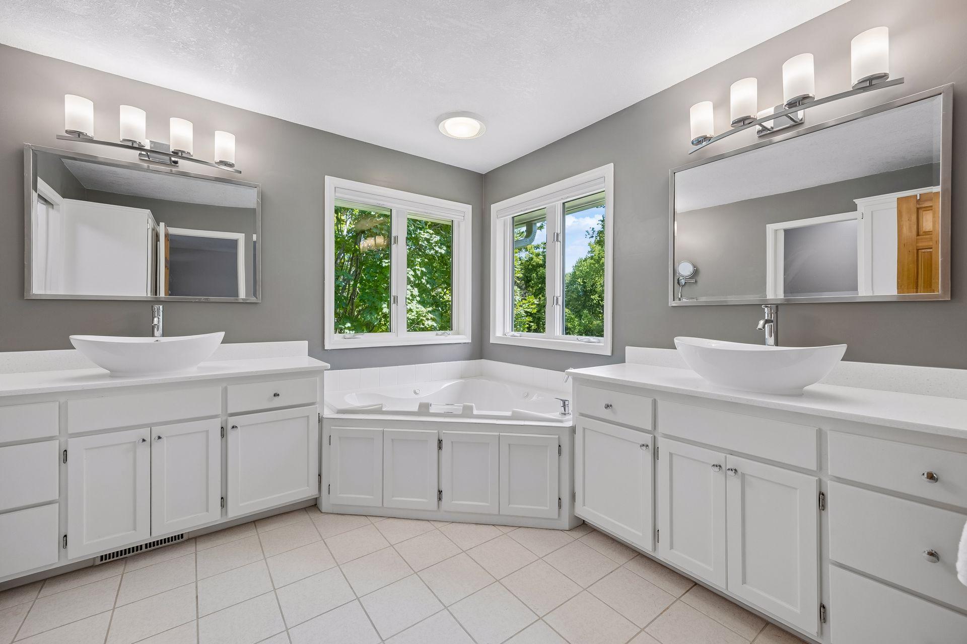 Beautifully updated primary bathroom featuring dual sinks, a jetted soaking tub, separate shower, and private toilet area.