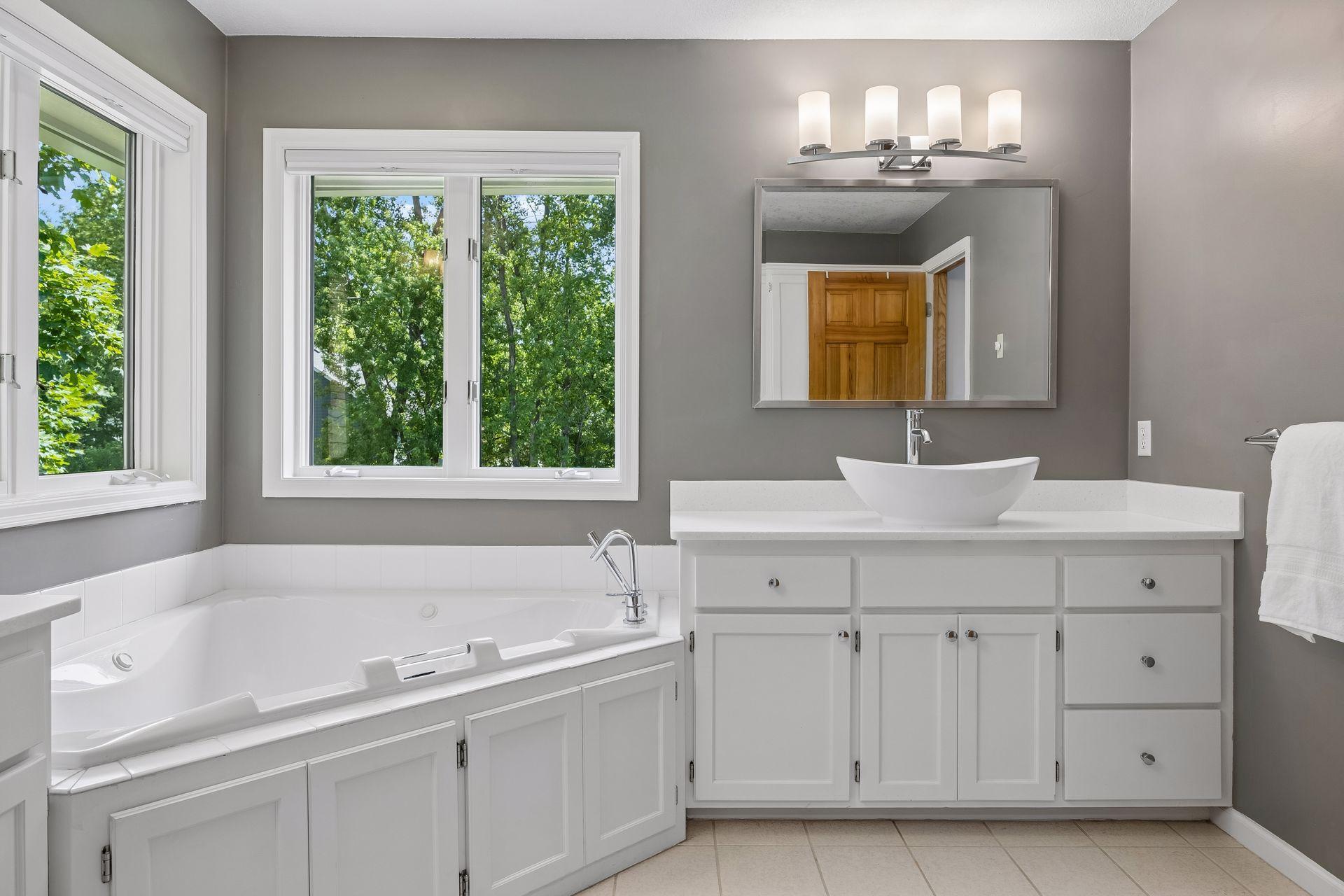 Beautifully updated primary bathroom featuring dual sinks, a jetted soaking tub, separate shower, and private toilet area.