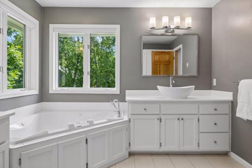 Beautifully updated primary bathroom featuring dual sinks, a jetted soaking tub, separate shower, and private toilet area.