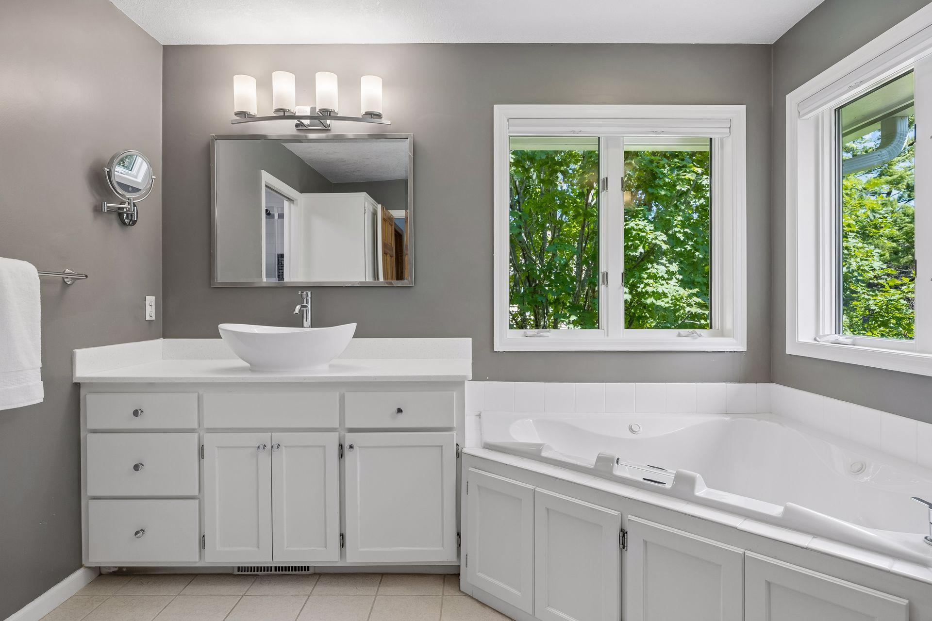 Beautifully updated primary bathroom featuring dual sinks, a jetted soaking tub, separate shower, and private toilet area.