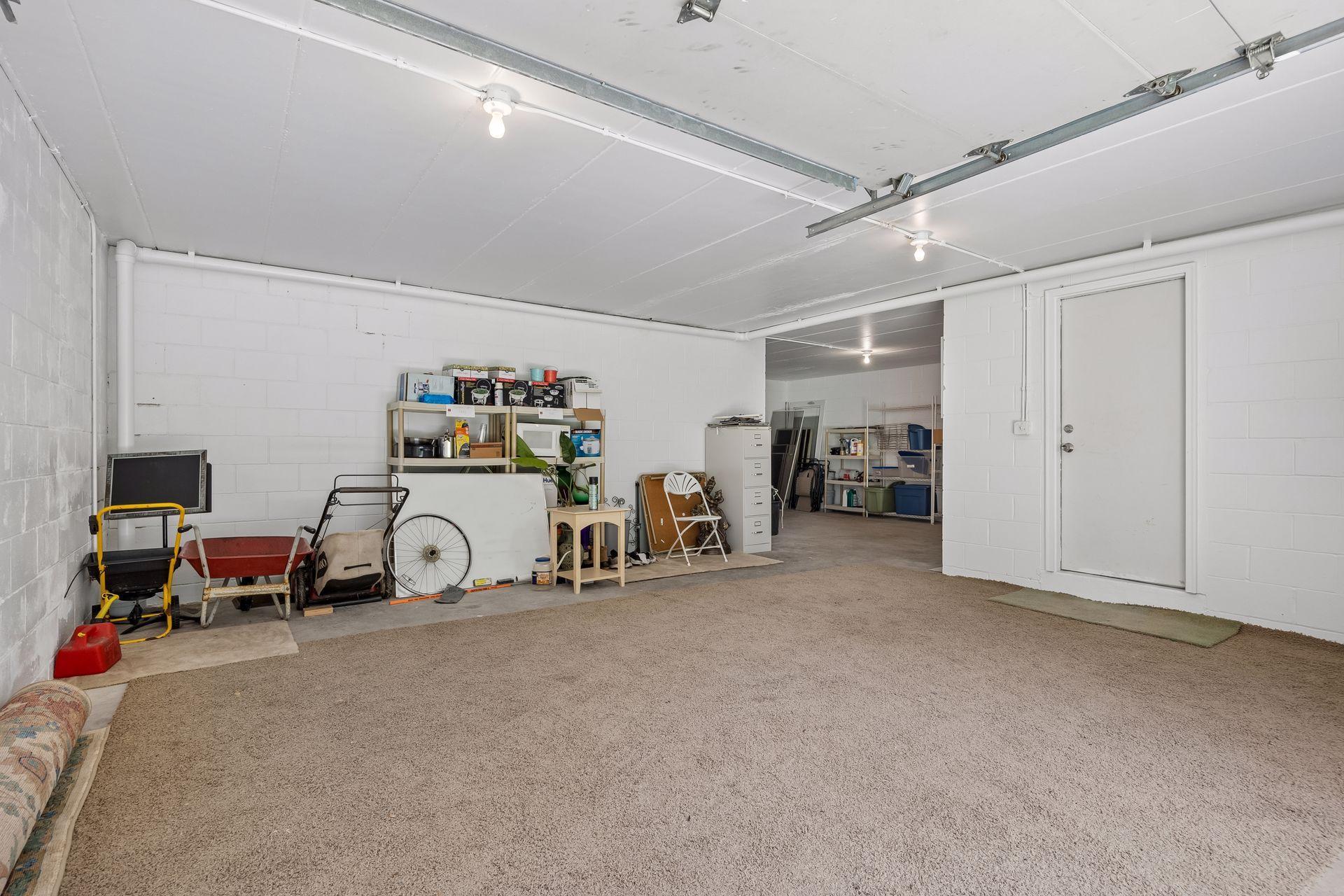 Additional 4th garage stall located at the back of the home, offering versatile space for a workshop, hobby or active space, or extra storage for yard equipment and more. **Note:** Carpet shown in the photo is not installed and will be removed.