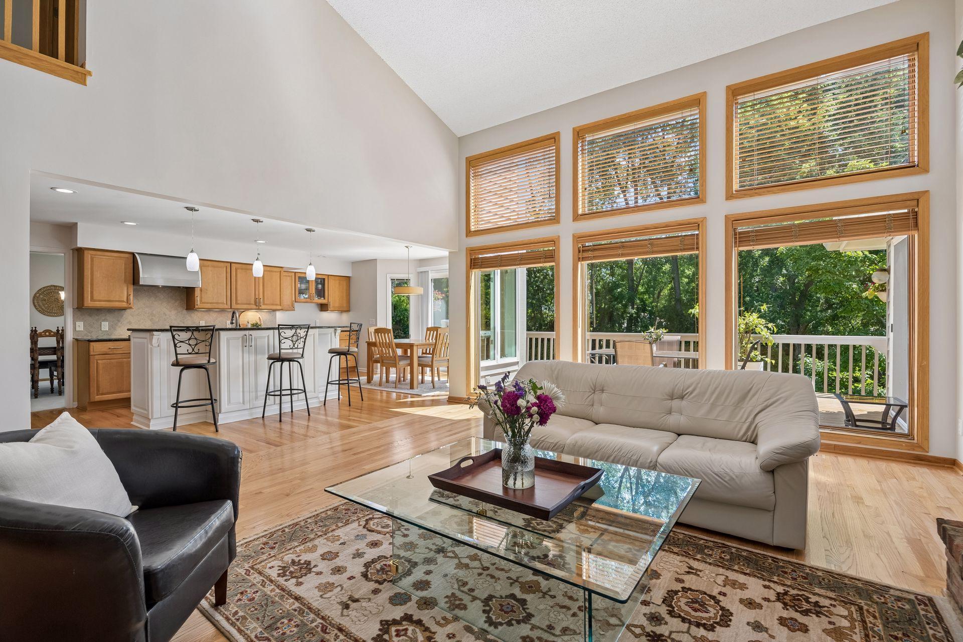 Spacious main family room with soaring two-story ceilings, flowing into a large, open kitchen designed for easy entertaining. Abundant natural light fills the space.