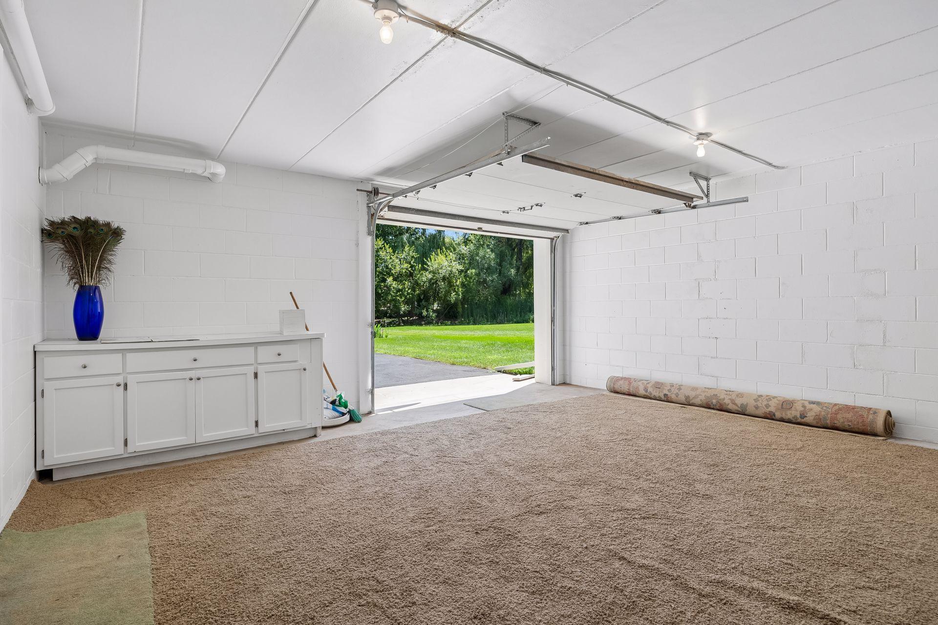 Additional 4th garage stall located at the back of the home, offering versatile space for a workshop, hobby or active space, or extra storage for yard equipment and more. **Note:** Carpet shown in the photo is not installed and will be removed.