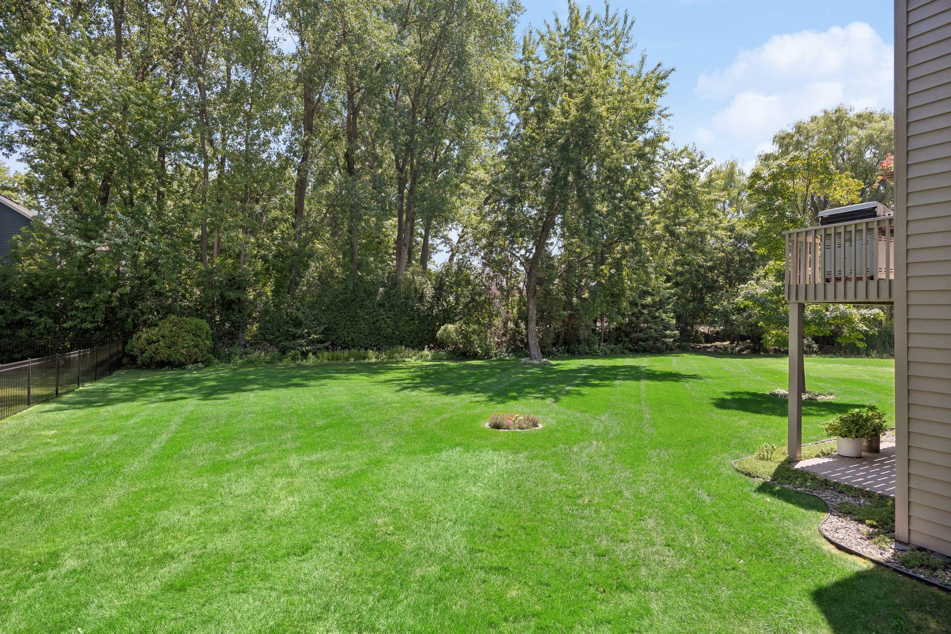 Large, flat, private backyard surrounded by mature trees, offering a peaceful setting with plenty of space for outdoor living, entertaining, and recreation.