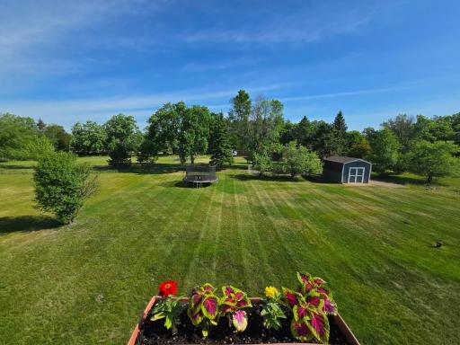 The stunning view from the backside deck showcases the wonderful backyard and storage shed.