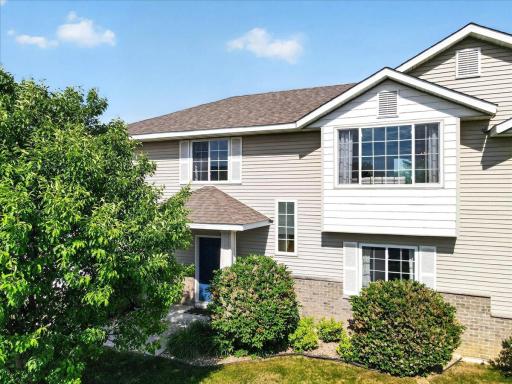 Charming front elevation featuring mature trees, established landscaping, and a welcoming covered entry.