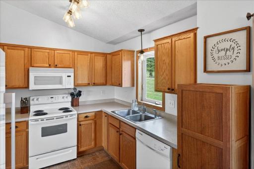 The kitchen features abundant cabinetry, ample prep space, and a window overlooking the peaceful backyard green space.