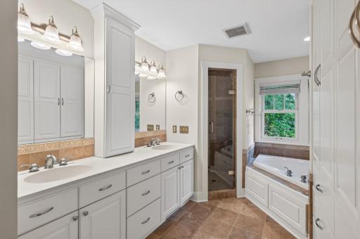 Designed as a private retreat, the luxurious primary bath offers heated tile floors, a relaxing soaking tub, dual vanities, and a beautifully appointed walk-in shower.