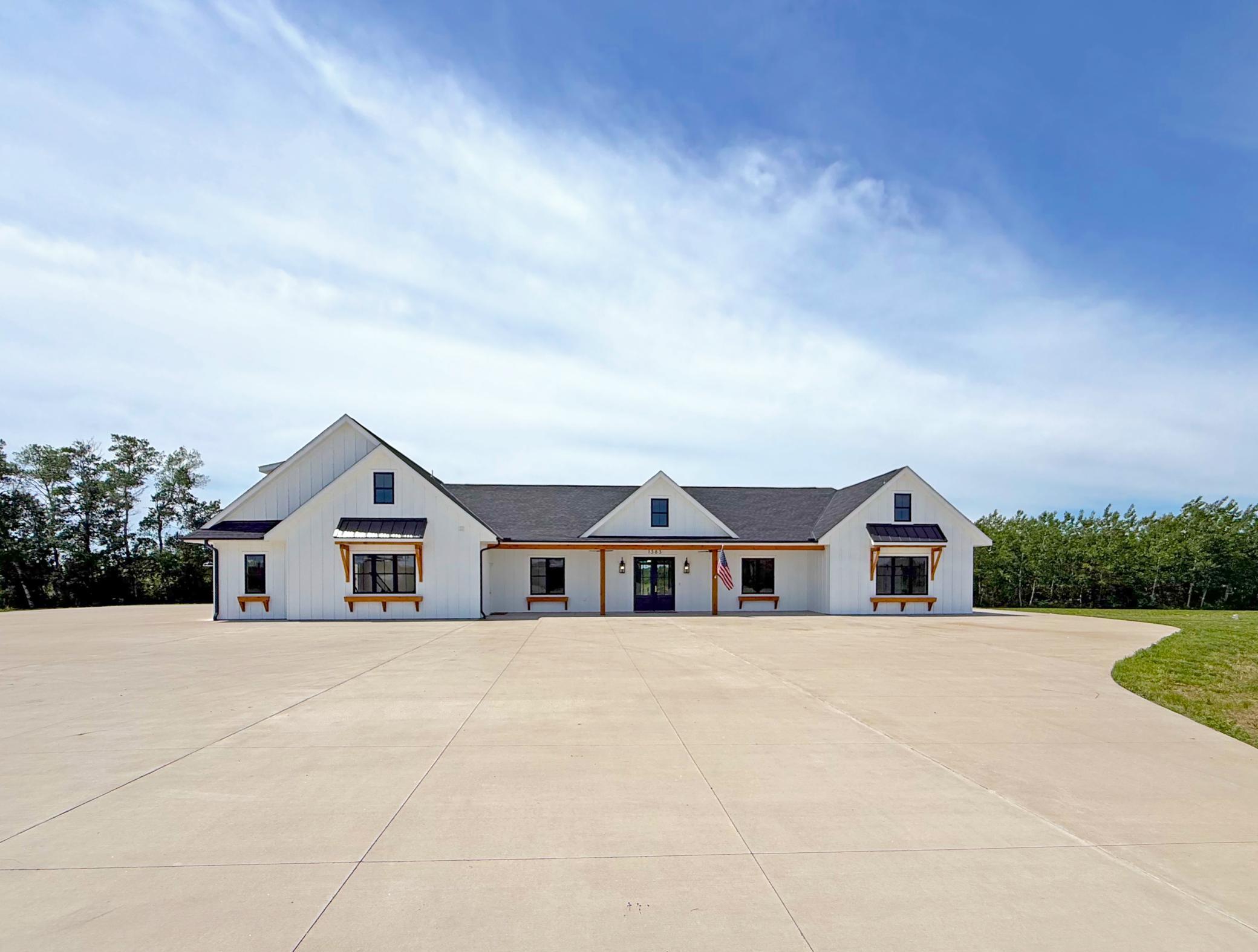 This striking custom home makes an unforgettable first impression with its clean architectural lines, modern farmhouse design, and expansive concrete approach.