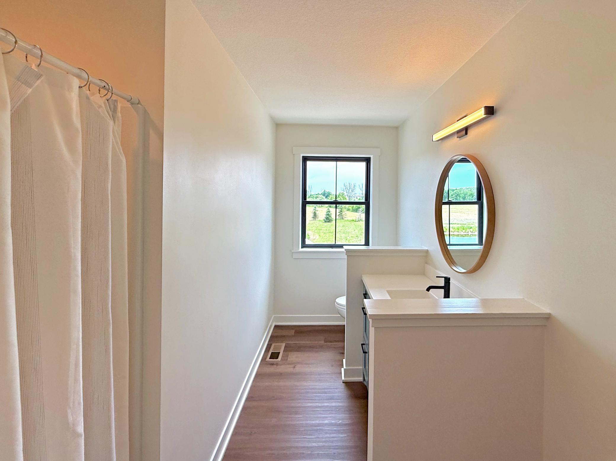 The upper-level bathroom is thoughtfully designed to serve family and guests, featuring a spacious vanity, modern fixtures, and a large window.