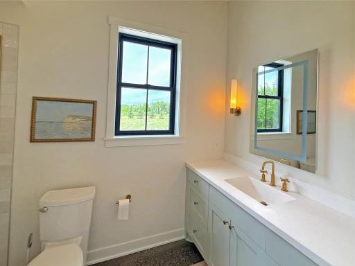 The well-appointed bath includes a tiled walk-in shower, custom vanity, and large window that fills the space with natural light, creating a bright retreat.