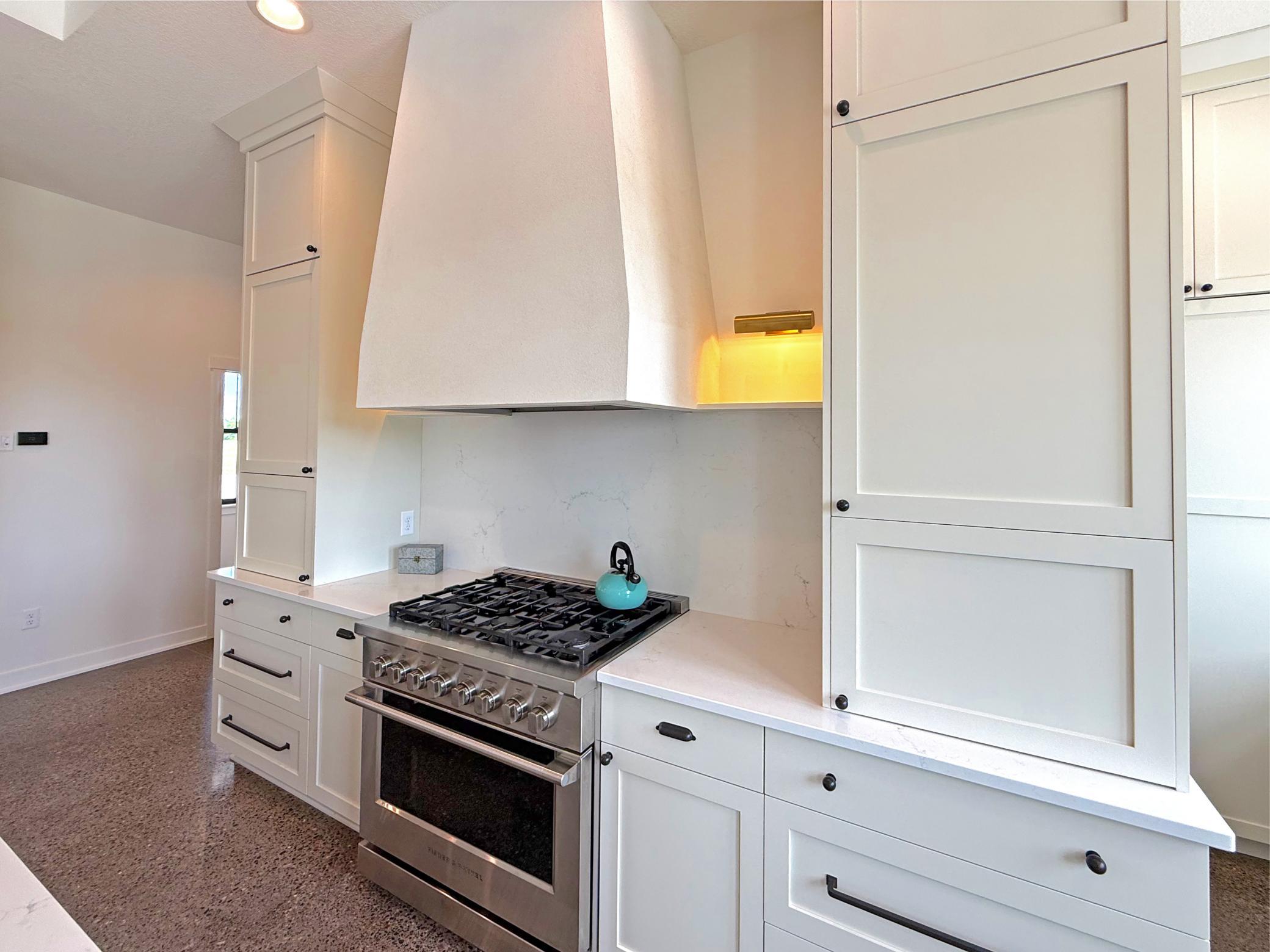This gourmet kitchen is thoughtfully designed with custom cabinetry, high-end gas stove, and a striking custom range hood that serves as a centerpiece of the space.