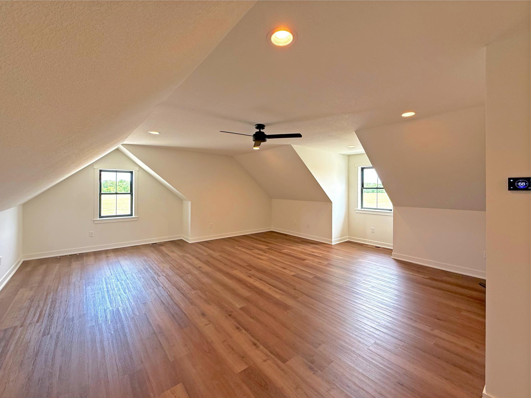 The upper-level bedroom offers a spacious and private retreat, featuring charming dormered ceilings, abundant natural light, and plenty of room for guests.