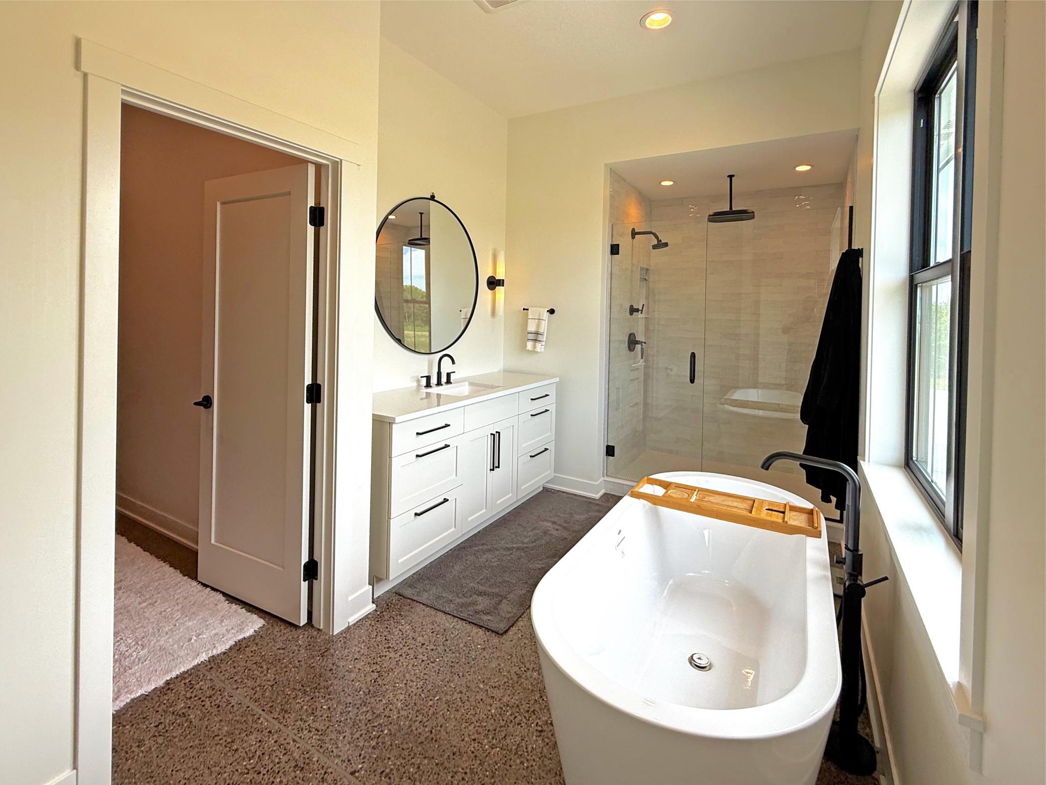 A sliding barn door leads to the luxurious en-suite bath, featuring a soaking tub, walk-in tile shower, and thoughtfully designed finishes.