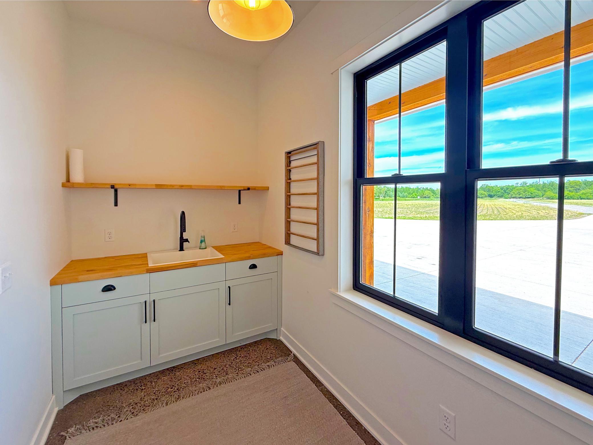 The main-level laundry room combines practicality with custom design, featuring a custom wall-mounted drying rack adds thoughtful functionality.