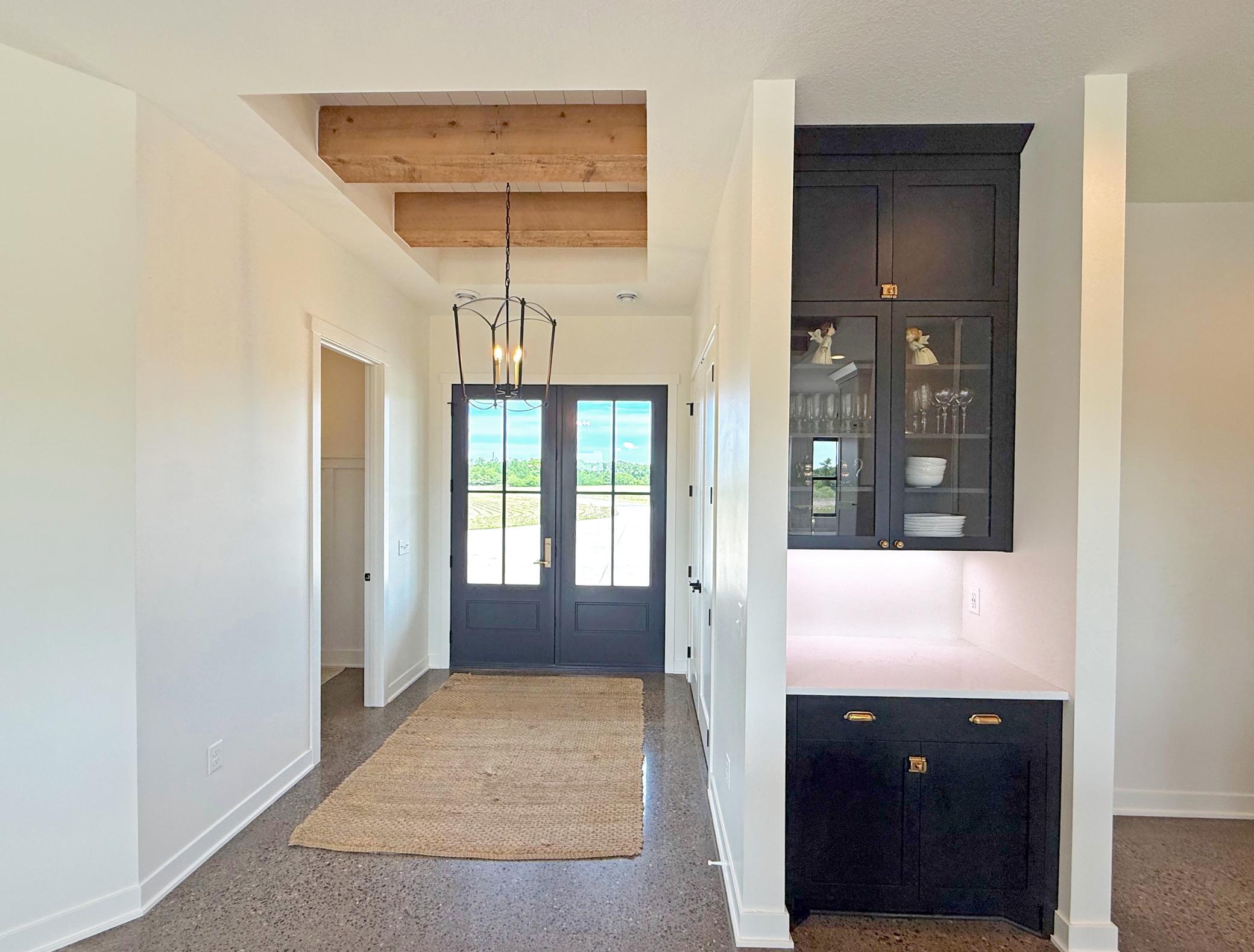 The welcoming foyer makes a memorable first impression with an impressive 8-foot front door, reclaimed wood beam accents, and abundant natural light.