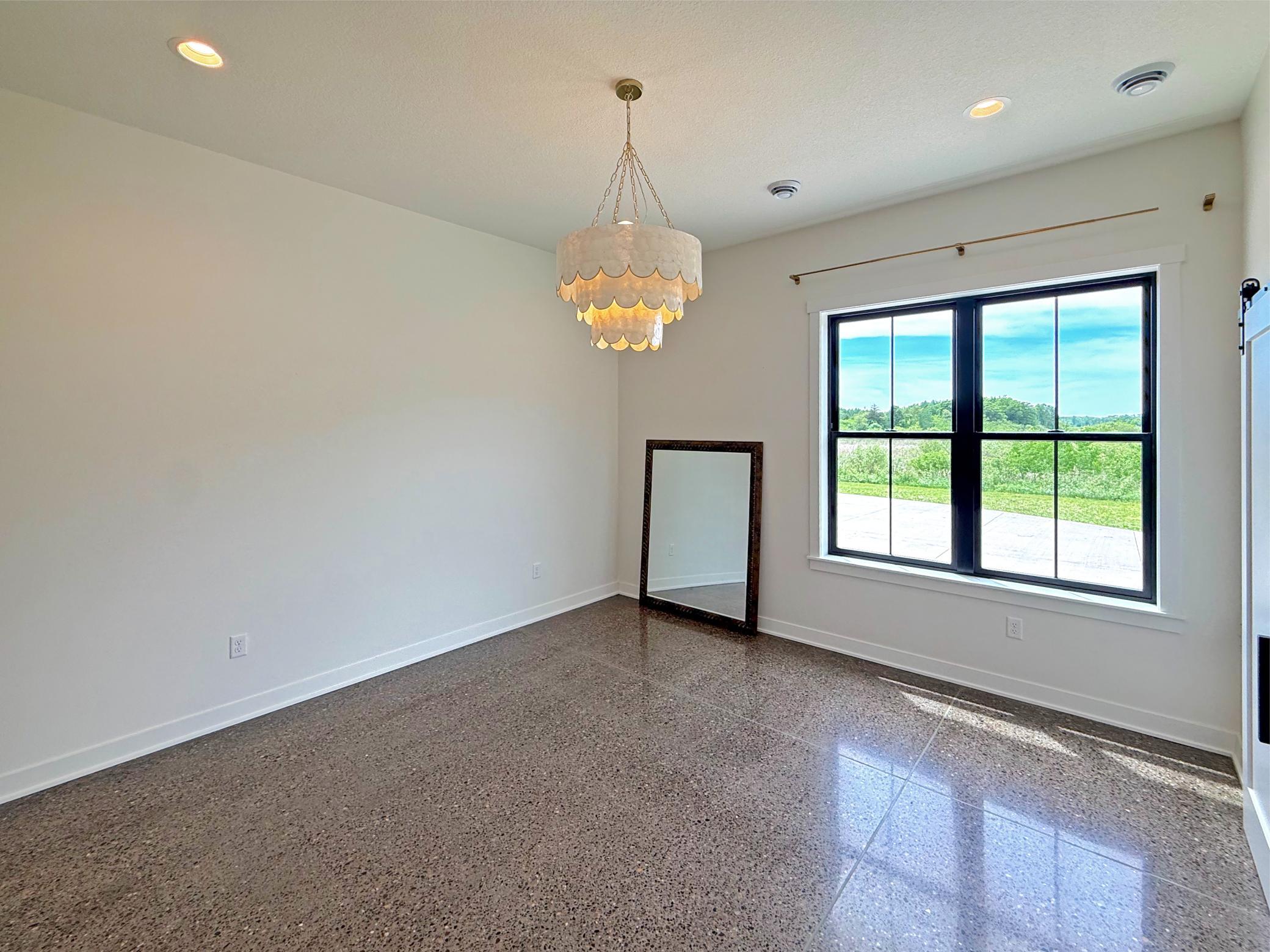 The second main-level bedroom offers an inviting space for family or guests, featuring large windows that capture beautiful countryside views.