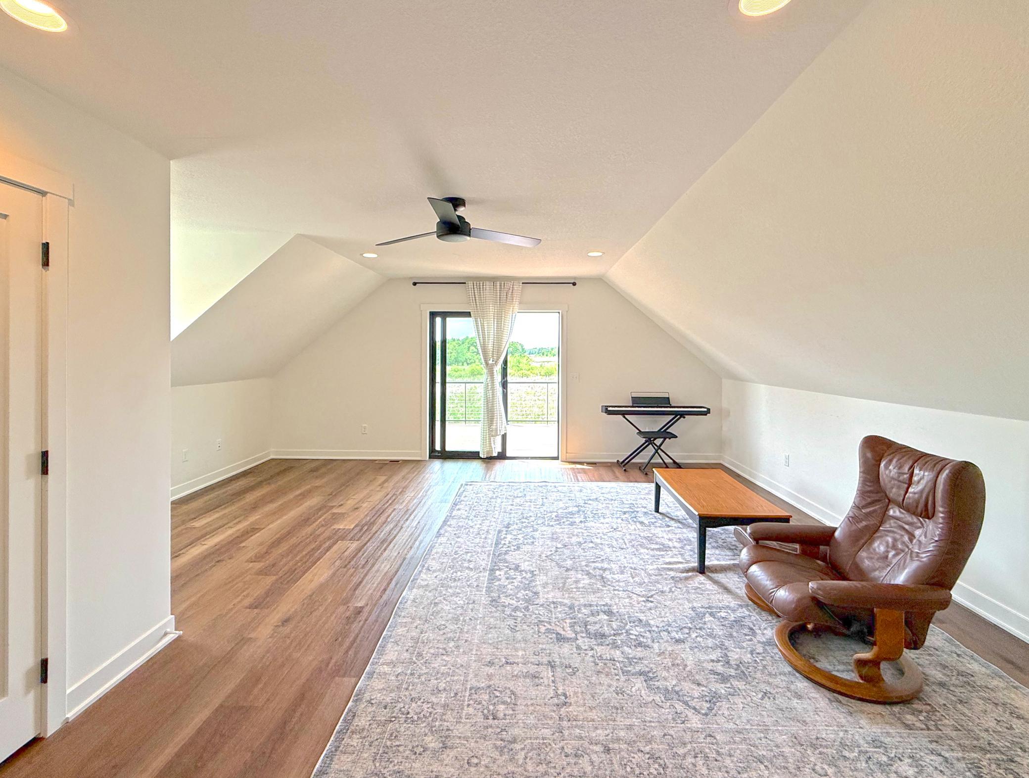 Vaulted ceilings and dormered architecture create a bright, open feel, while patio doors lead to a private balcony overlooking the surrounding countryside.
