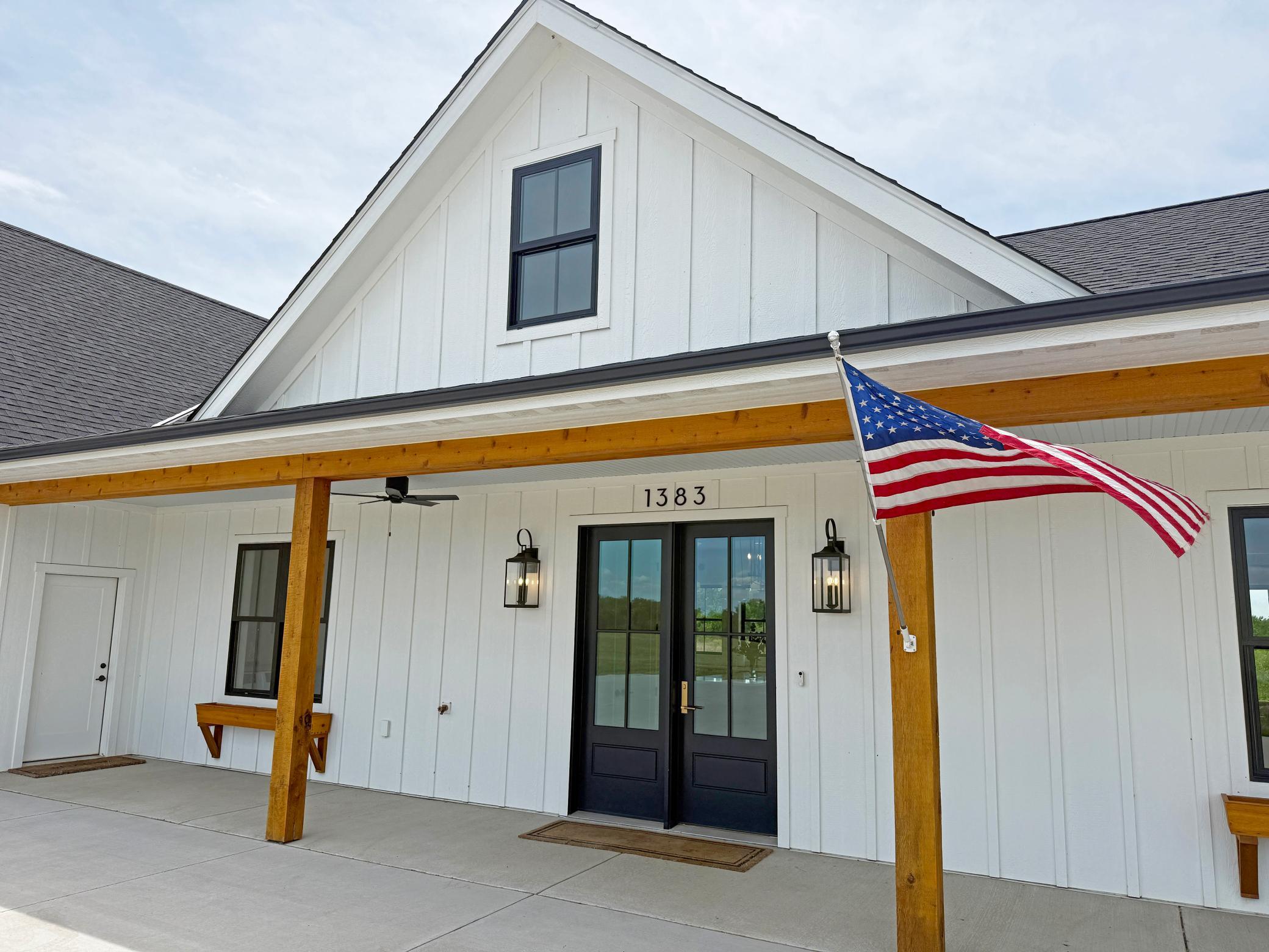 The welcoming covered front porch creates a warm and inviting first impression, highlighted by striking timber accents, modern lighting, and beautiful double front doors.